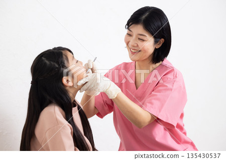 一位女牙醫正在檢查一名兒童患者。 135430537