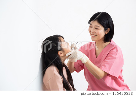 A female dentist examining a child patient A female dentist examining a child patient 135430538