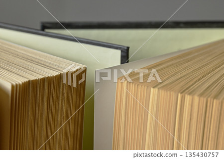 A detailed shot of multiple open books showing paper edges, textures, and hardcover binding details 135430757