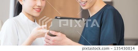 醫護人員一邊看著平板電腦一邊進行團隊協作解說。注意護理師的5W1H交班流程。不要露臉。 醫護人員一邊看著平板電腦一邊進行團隊協作解說。注意護理師的5W1H交班流程。不要露臉。 135430814
