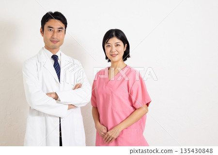 A male doctor and a female nurse smiling at the camera A male doctor and a female nurse smiling at the camera 135430848