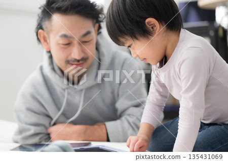 Father and son learning together on a tablet during the holidays. Father and son learning together on a tablet during the holidays. 135431069