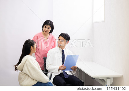 A male doctor examining an elementary school student patient and a female nurse supporting him 135431402