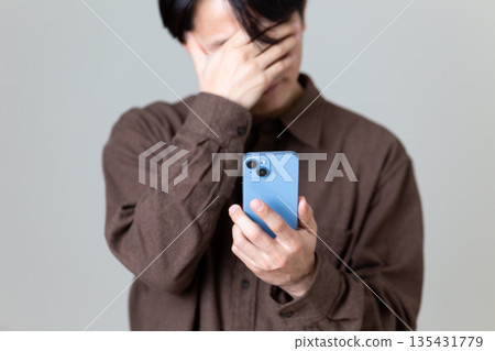 A middle-aged man looking at his smartphone and worrying A middle-aged man looking at his smartphone and worrying 135431779