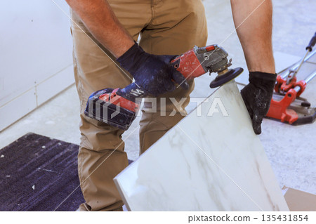 Worker uses cutting tool on marble tile in construction area Worker uses cutting tool on marble tile in construction area 135431854