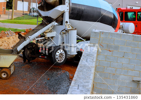 Construction site with cement mixer pouring concrete near freshly built walls Construction site with cement mixer pouring concrete near freshly built walls 135431860