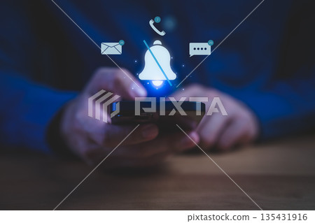 Person holding a smartphone with muted notification bell icon and message, call, and email alerts floating above, symbolizing do not disturb mode, focus time, or silenced notifications. 135431916
