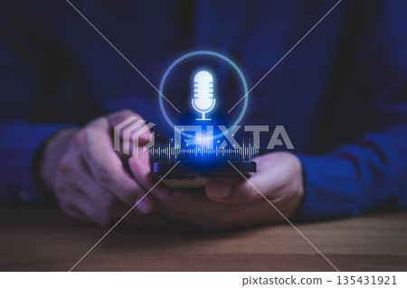Person holding smartphone with glowing microphone icon and sound wave hologram, symbolizing voice recognition, AI assistant, digital communication, and smart technology innovation in modern devices. Person holding smartphone with glowing microphone icon and sound wave hologram, symbolizing voice recognition, AI assistant, digital communication, and smart technology innovation in modern devices. 135431921