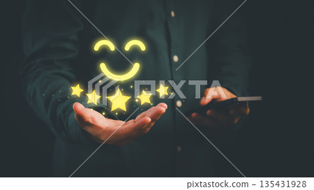Customer satisfaction concept showing five-star rating and smiling face icon on hand, symbolizing excellent service, positive feedback, customer service, and successful online business reputation. 135431928