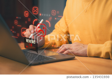 Negative online review concept showing a person using laptop with low rating icon and sad face, representing poor customer feedback, product dissatisfaction, digital reputation management issues. 135431930