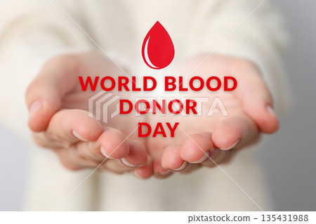 Hands hold a red drop, promoting blood donation 135431988