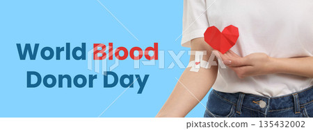Hand holding origami heart next to a bandage on arm 135432002