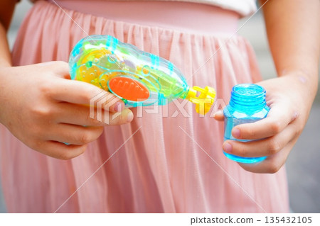 孩子的小手拿著泡泡液。夏日戶外玩耍的瞬間。 135432105