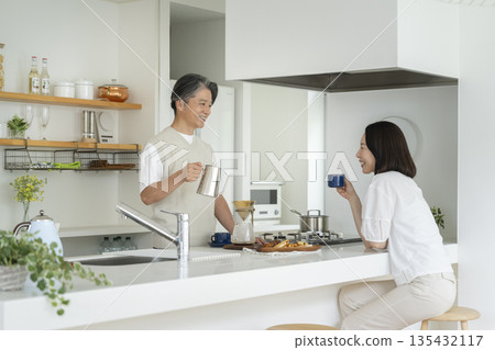 一對五十多歲的夫婦在廚房喝咖啡 一對五十多歲的夫婦在廚房喝咖啡 135432117