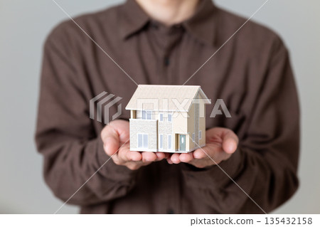 一位中年男子抱著一個模型房子 135432158