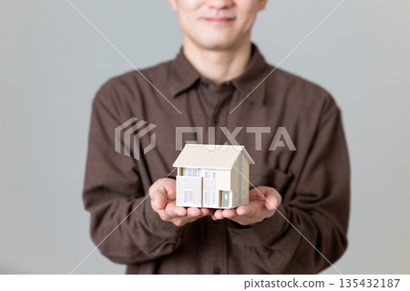 一位中年男子抱著一個模型房子 135432187
