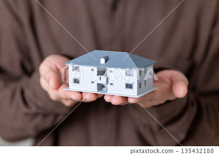 一位中年男子抱著一棟公寓大樓模型。 135432188