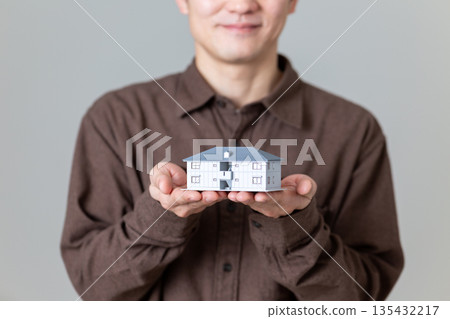 一位中年男子抱著一棟公寓大樓模型。 135432217