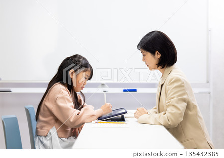 一位小學生正在接受補習班老師的輔導。 135432385