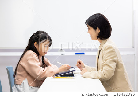 一位小學生正在接受補習班老師的輔導。 135432389