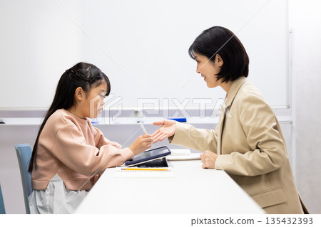 一位小學生正在接受補習班老師的輔導。 135432393