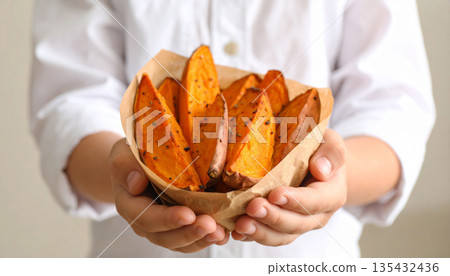 A roasted sweet potato in hand - a warm autumn/winter food image 135432436