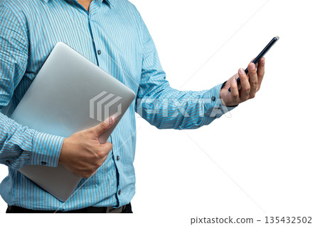 Close-up of Asian man in striped shirt holding a laptop and using smartphone, representing modern business communication, remote work, digital productivity, and multitasking in professional lifestyle 135432502