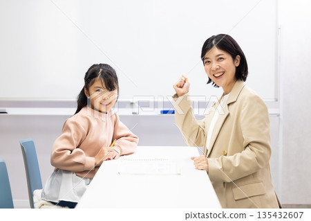 Smiling female cram school teacher and female student in classroom 135432607