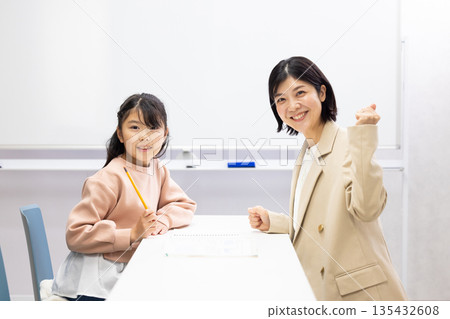 Smiling female cram school teacher and female student in classroom 135432608