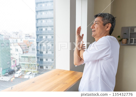 一位老人在窗邊伸展身體。 一位老人在窗邊伸展身體。 135432776