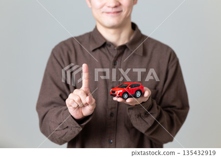 一位中年男子手持模型車，食指向上指著。 135432919