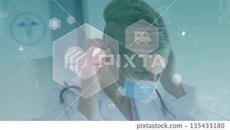 Adjusting physician in lab coat securing surgical mask in hospital corridor, with hexagon icons 135433180