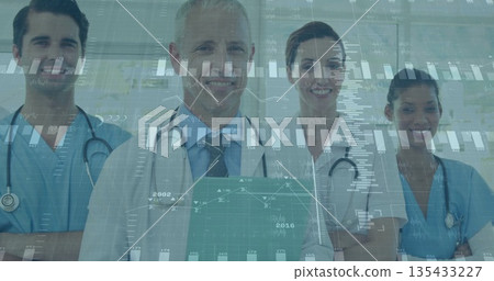 Presenting medical team showing digital charts in hospital corridor, with scrubs and stethoscopes 135433227