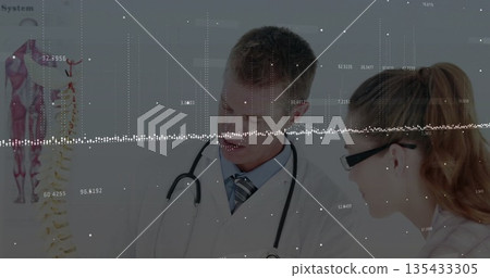 Two medical professionals examining spine model and pointing in consultation room Two medical professionals examining spine model and pointing in consultation room 135433305