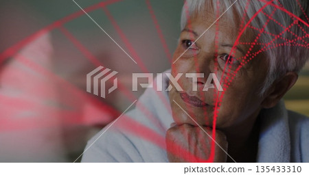 Resting chin senior woman in bathrobe gazing in bedroom, with red geometric projection patterns 135433310