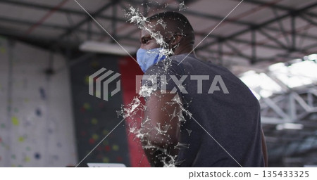 Standing man wearing grey tee, blue face mask inside climbing gym, with holds, fractal overlay Standing man wearing grey tee, blue face mask inside climbing gym, with holds, fractal overlay 135433325