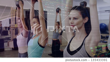 Lifting six women raising kettlebells overhead at gym studio with graph overlay, copy space 135433391