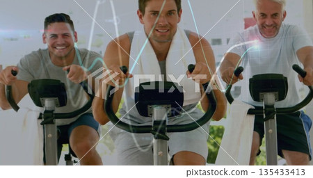 Pedaling center rider wearing sleeveless shirt with towel around neck in gym with stationary bikes 135433413