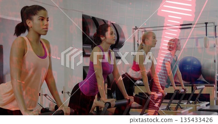 Four women leaning forward on reformers in pilates studio, with mats, foam rollers, stability ball Four women leaning forward on reformers in pilates studio, with mats, foam rollers, stability ball 135433426