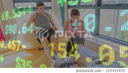 Rowing client sporting gear on gym rower beside exercise ball, trainer using tablet and stylus Rowing client sporting gear on gym rower beside exercise ball, trainer using tablet and stylus 135433433