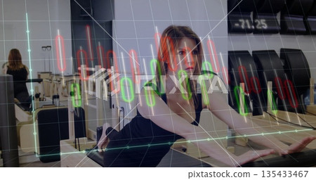 Female athlete performing pilates stretch on reformer in fitness studio, candlestick overlay Female athlete performing pilates stretch on reformer in fitness studio, candlestick overlay 135433467
