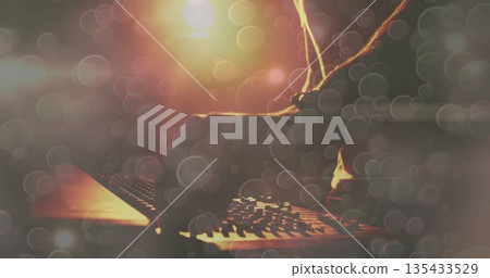 Twisting DJ arm in dark sleeve adjusting mixer knobs on nightclub stage, with warm light bokeh 135433529