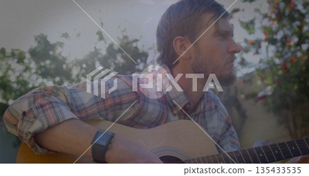 Strumming acoustic guitar musician wearing plaid shirt and smartwatch in backyard, copy space Strumming acoustic guitar musician wearing plaid shirt and smartwatch in backyard, copy space 135433535