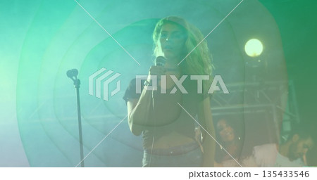 Singing lead singer holding wired microphone at concert stage, with spotlights fog haze truss 135433546