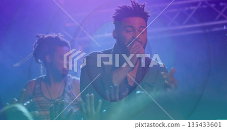Singing singer wearing dark shirt holding mic gesturing on stage with bass guitar truss and lights Singing singer wearing dark shirt holding mic gesturing on stage with bass guitar truss and lights 135433601