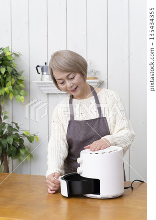 Senior woman making snack potato chips in an air fryer 135434355