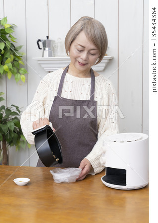 一位老年婦女用氣炸鍋製作薯片零食 135434364