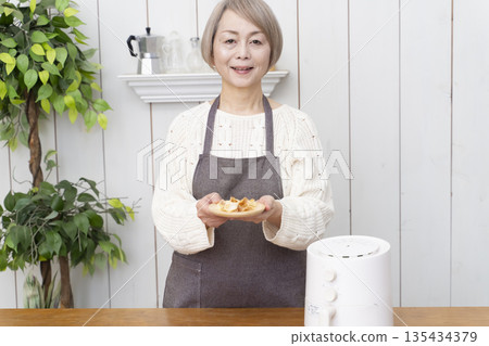 Senior woman making snack potato chips in an air fryer Senior woman making snack potato chips in an air fryer 135434379