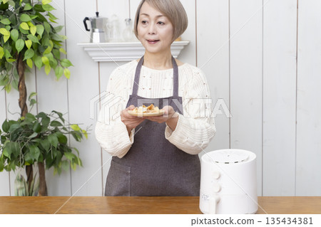 Senior woman making snack potato chips in an air fryer Senior woman making snack potato chips in an air fryer 135434381