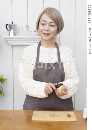 Senior woman making snack potato chips in an air fryer 135434391